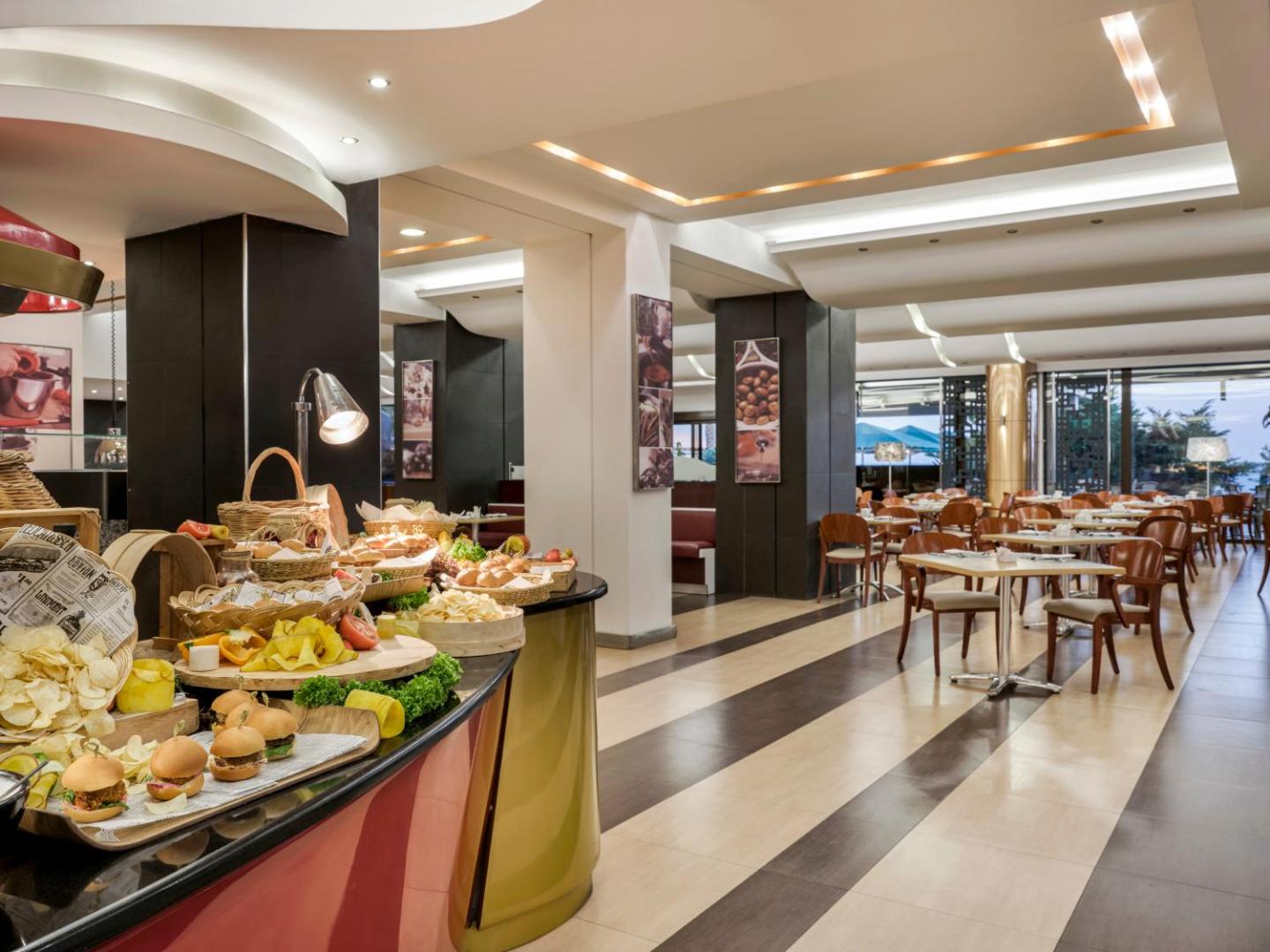 Bufetes galds ar dažādām uzkodām, maizi un burgeriem viesnīcas restorānā.