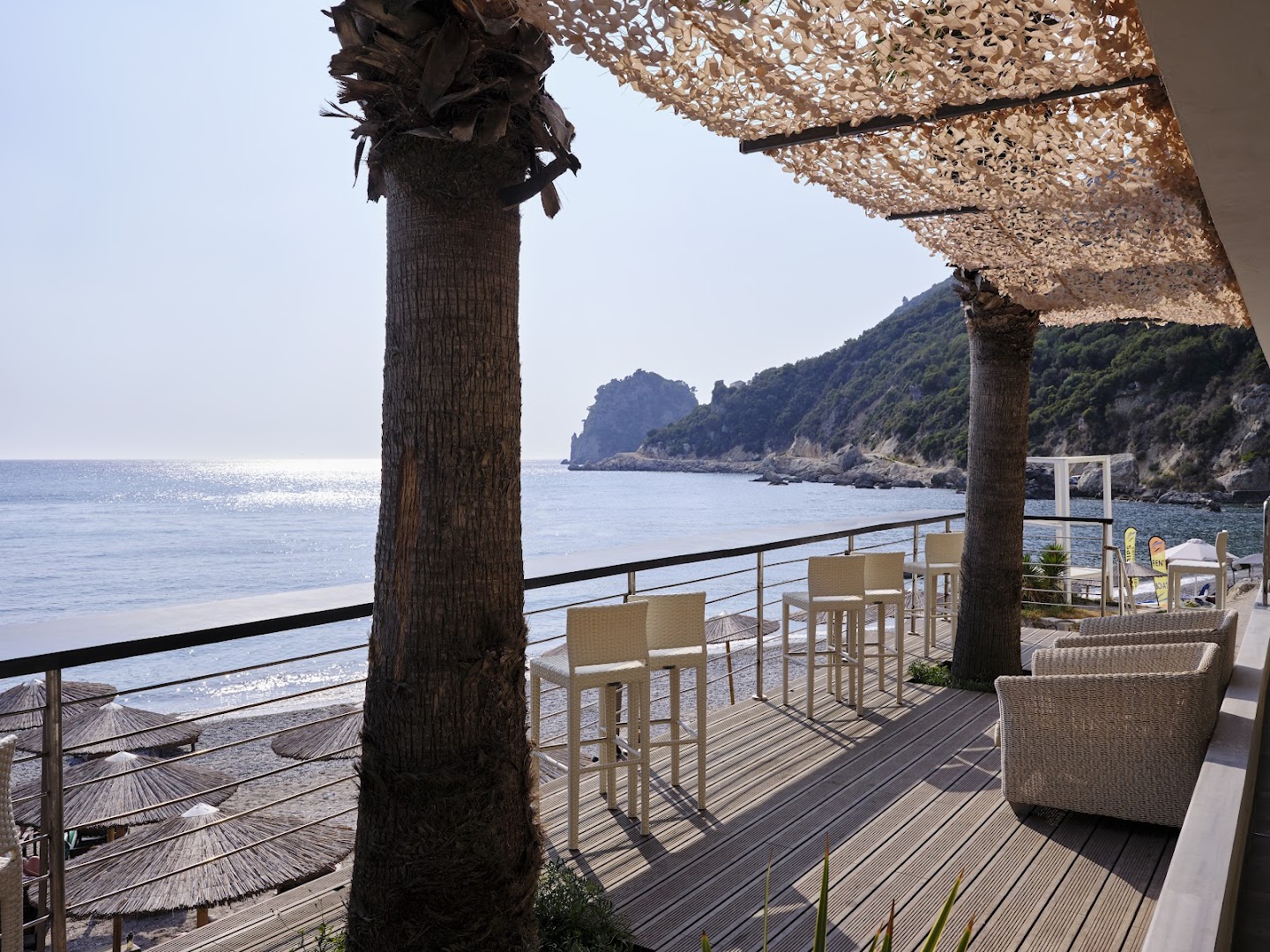 Atlantica Grand Mediterraneo Resort āra terase ar skatu uz Jonijas jūru un klintīm Korfu piekrastē — bāra krēsli un atpūtas zona