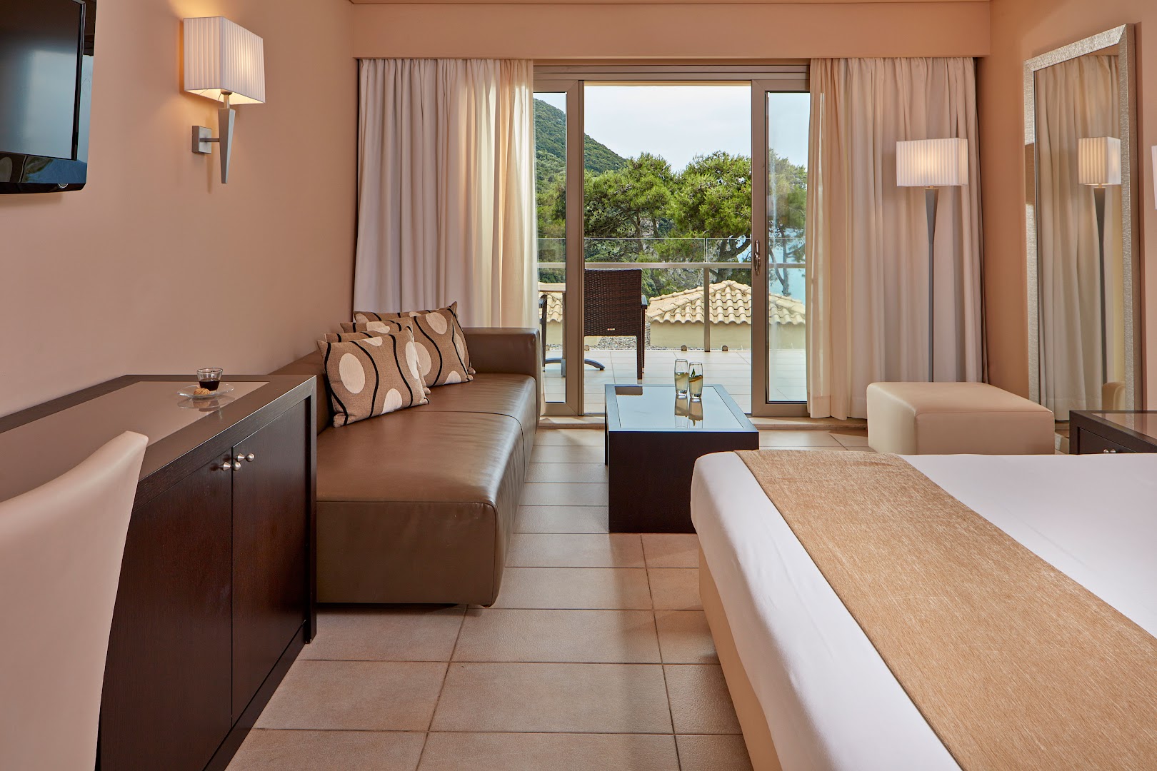 Atlantica Grand Mediterraneo Resort numurs ar dīvānu un terasi, no kuras paveras skats uz priežu mežu