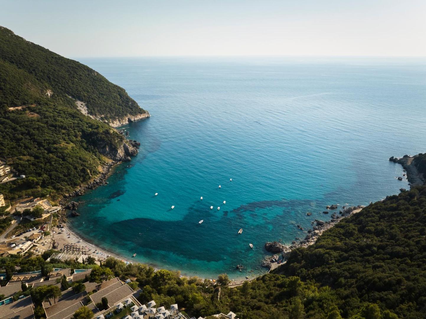 Atlantica Grand Mediterraneo Resort skats no putna lidojuma uz privāto līci un pludmali Korfu salā ar dzidru tirkīza ūdeni