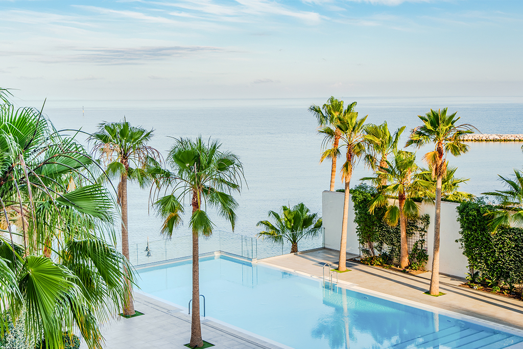 Spirit Hotel Benalmadena Beach baseins ar pārplūdes malu, ko ieskauj palmas un skats uz zilo Vidusjūru Costa del Sol reģionā.