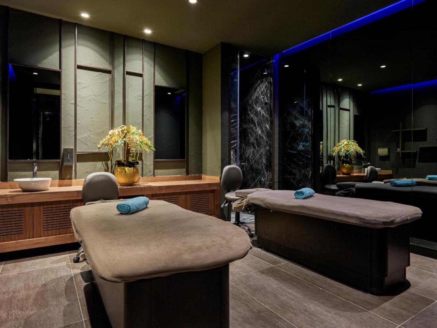 Mūsdienīgs spa procedūru numurs Voyage Sorgun kūrortā ar divām masāžas gultām, tumši zaļām sienām un elegantu apgaismojumu