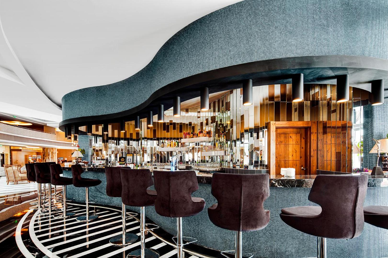 TUI Magic Life Jacaranda modernais lobby bārs ar augstiem krēsliem un spoguļu apdari pie letes