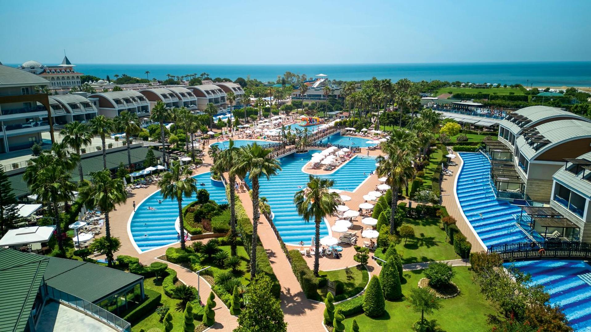 TUI Magic Life Jacaranda panorāmas skats uz plašo baseinu kompleksu, dārzu un Vidusjūras piekrasti Sidē, Turcijā saulainā dienā
