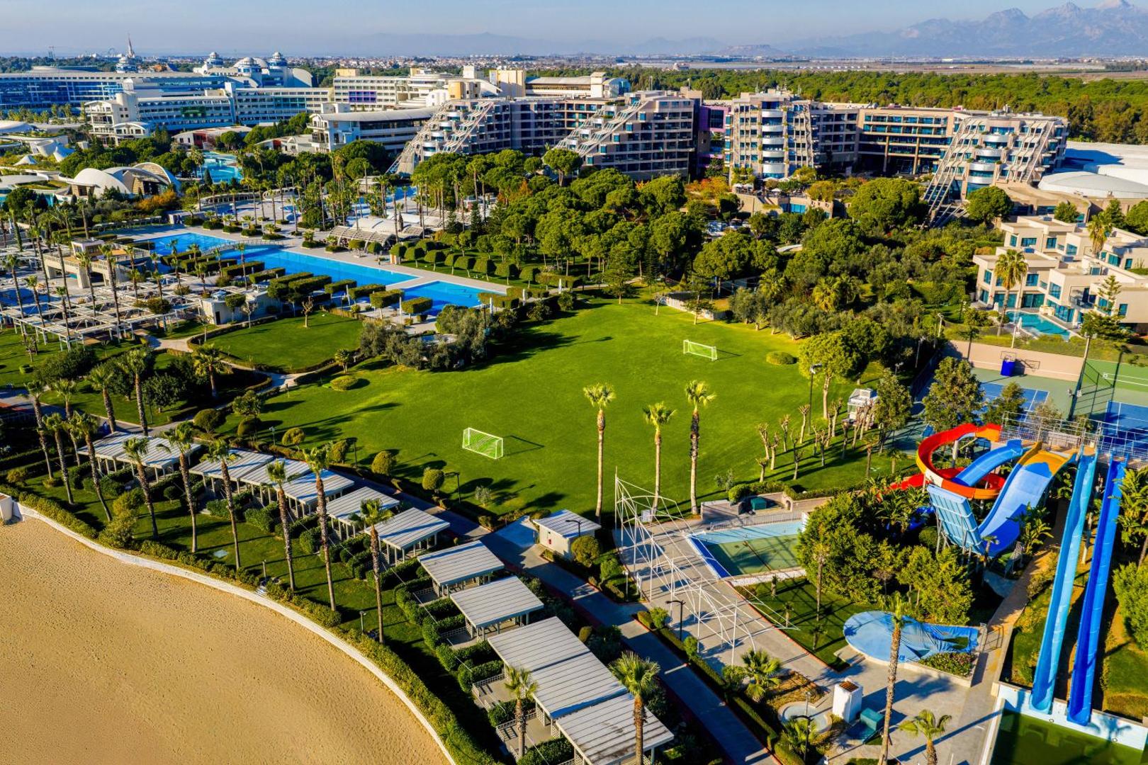Susesi Luxury Resort plašā teritorija Belekā no putna lidojuma — baseini, dārzi, akvaparks un viesnīcas korpusi pie jūras