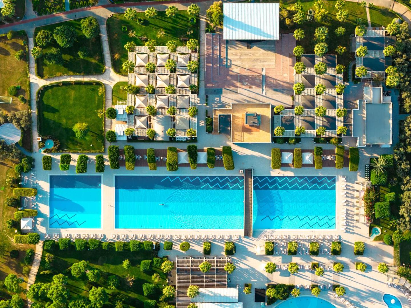 Susesi Luxury Resort plašā teritorija ar taisnstūra peldbaseiniem, koptu dārzu un atpūtas terasēm Belekas piekrastē