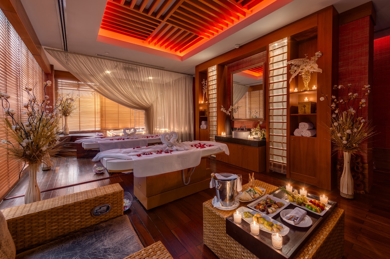 Susesi Luxury Resort spa procedūru telpa pāriem ar masāžas galdiem, svecēm, augļiem un romantisku apgaismojumu koka interjerā