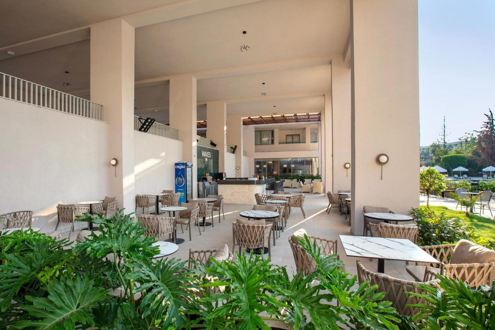 Viesnīcas Greenwood Kemer Resort āra bārs Waves ar modernām mēbelēm, marmora galdiņiem un zaļiem augiem pie baseina zonas