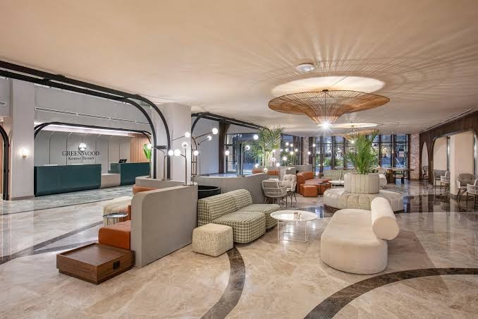 Greenwood Kemer Resort plašais un modernais lobby vestibils ar dizaina mēbelēm, atpūtas zonām un recepcijas galdu Kemeras viesnīcā