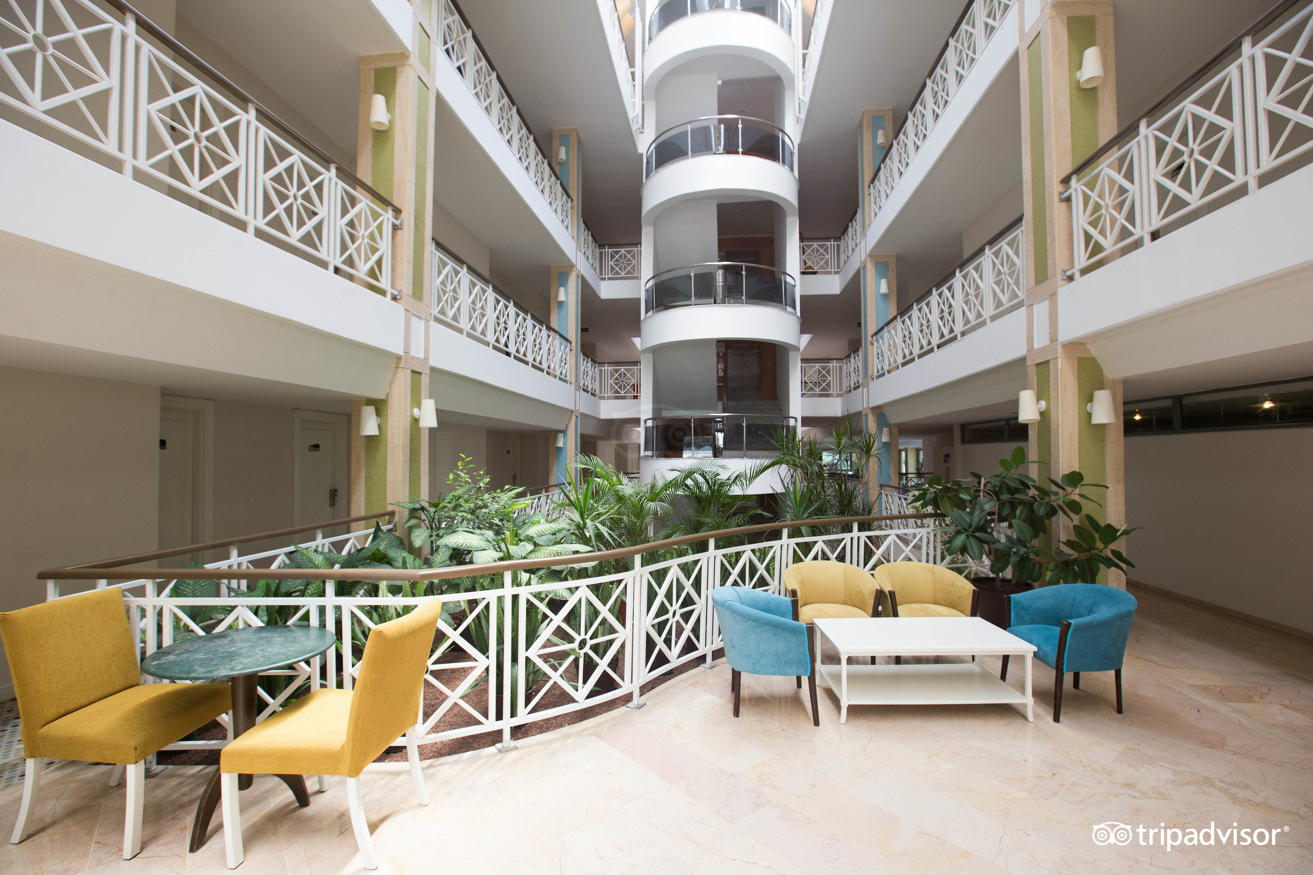 Greenwood Kemer Resort viesnīcas iekšpagalms ar atpūtas zonu, krāsainiem krēsliem un telpaugiem vairākos stāvos Antalijas reģionā, Turcijā