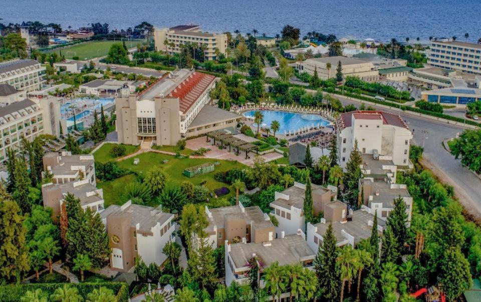Greenwood Kemer Resort panorāmas skats no putna lidojuma uz viesnīcas teritoriju, baseinu, dārzu un Vidusjūras piekrasti Kemeras reģionā.