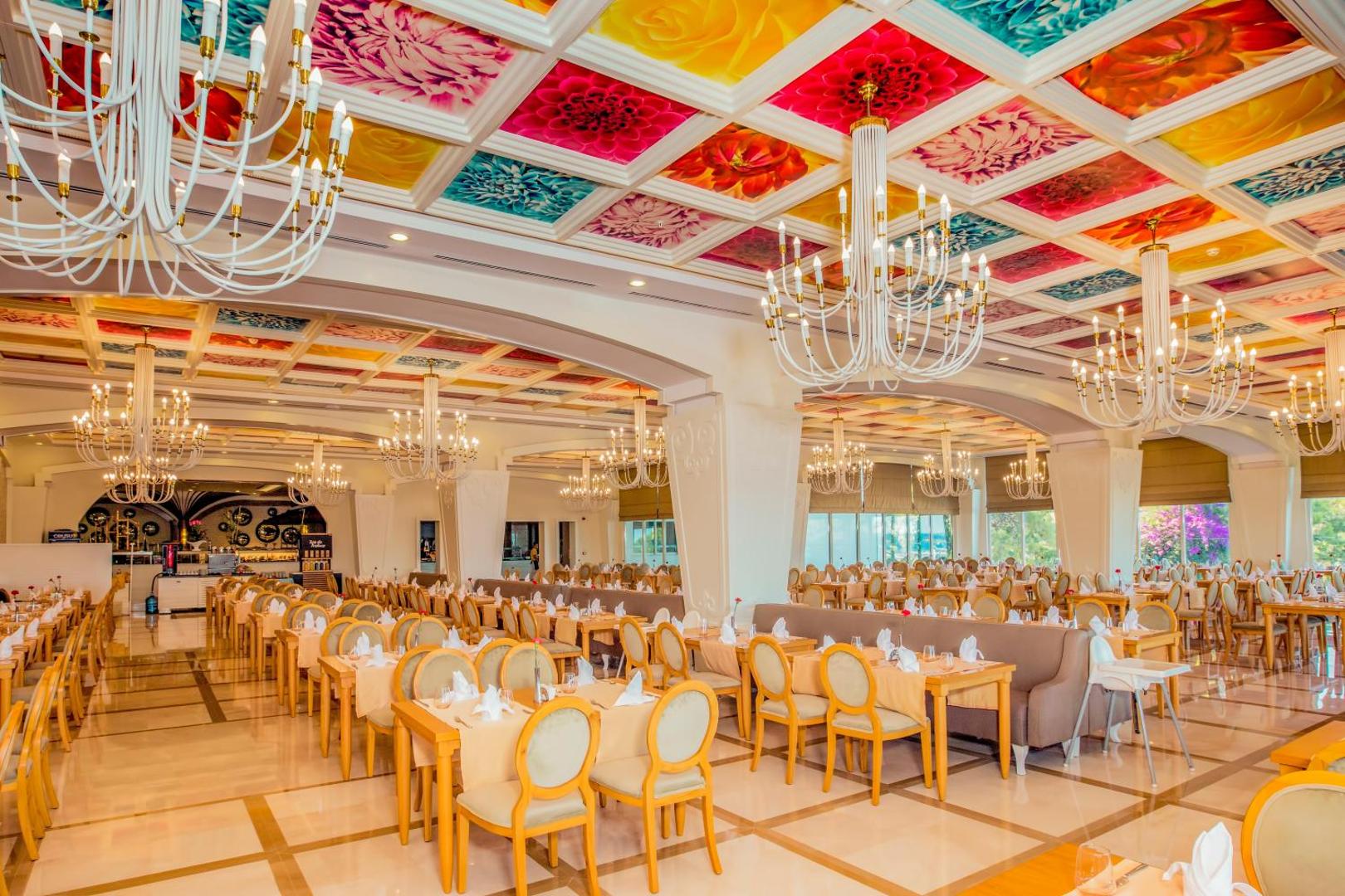 Sherwood Exclusive Kemer galvenais restorāns ar krāsainiem griestu dekoriem, greznām lustrām un eleganti klātiem galdiem