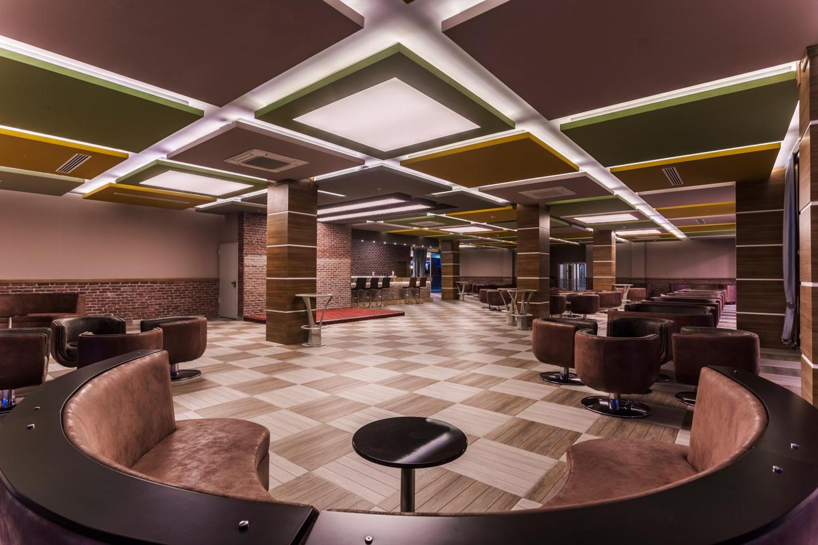 Lonicera Resort & Spa viesnīcas plašā atpūtas zāle ar moderniem krēsliem, šaha galdiņa grīdas segumu un dekoratīviem griestu paneļiem