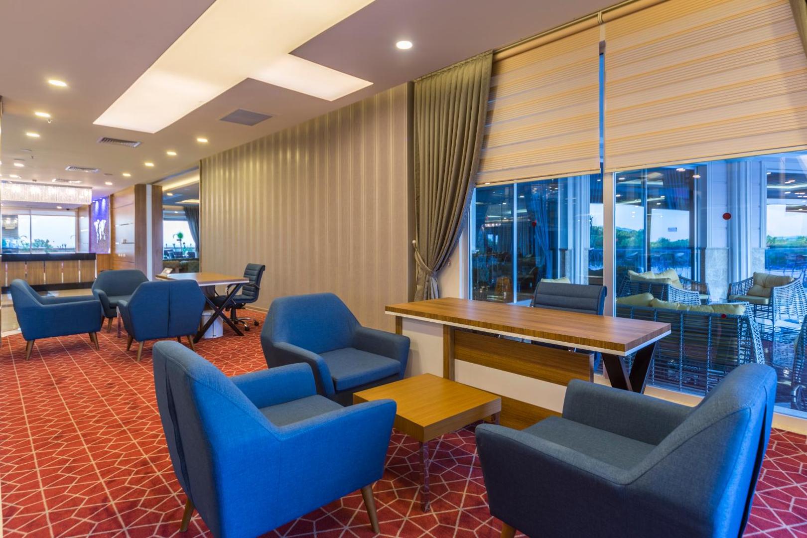 Lonicera Resort & Spa Hotel atpūtas zona ar ziliem atpūtas krēsliem, koka galdiem un lieliem logiem, kas vērsti uz terasi