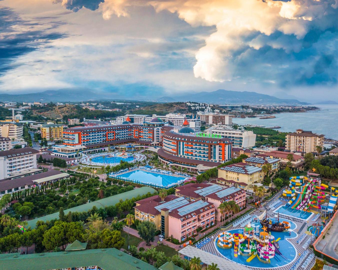Lonicera Resort & Spa viesnīcas komplekss no augšas ar skatu uz akvaparku, dārziem un piekrasti saulrieta laikā