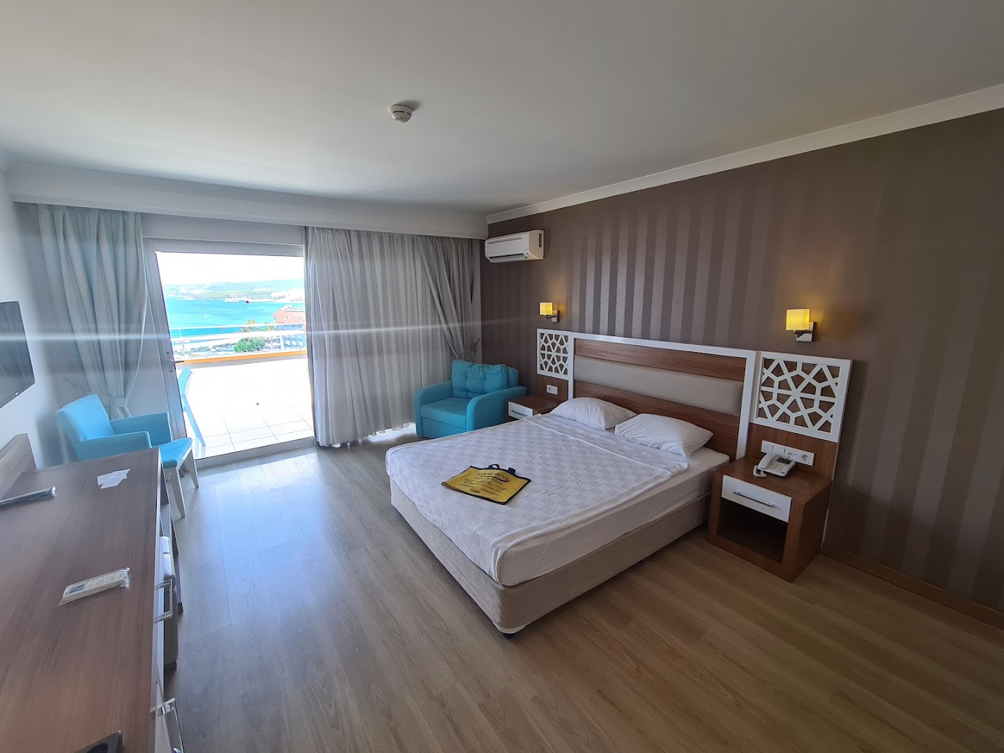 Lonicera Resort & Spa Hotel numura interjers ar balkonu, no kura paveras skats uz piekrasti un zilo jūru Turcijā