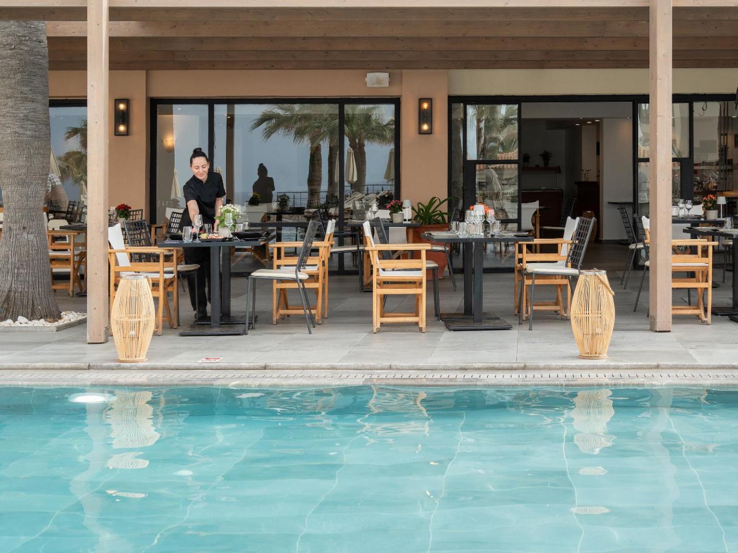 Grecotel Marine Palace & Aqua Park ēdienkartes restorāna āra terase pie baseina — galdiņu servēšana un personāls darbā