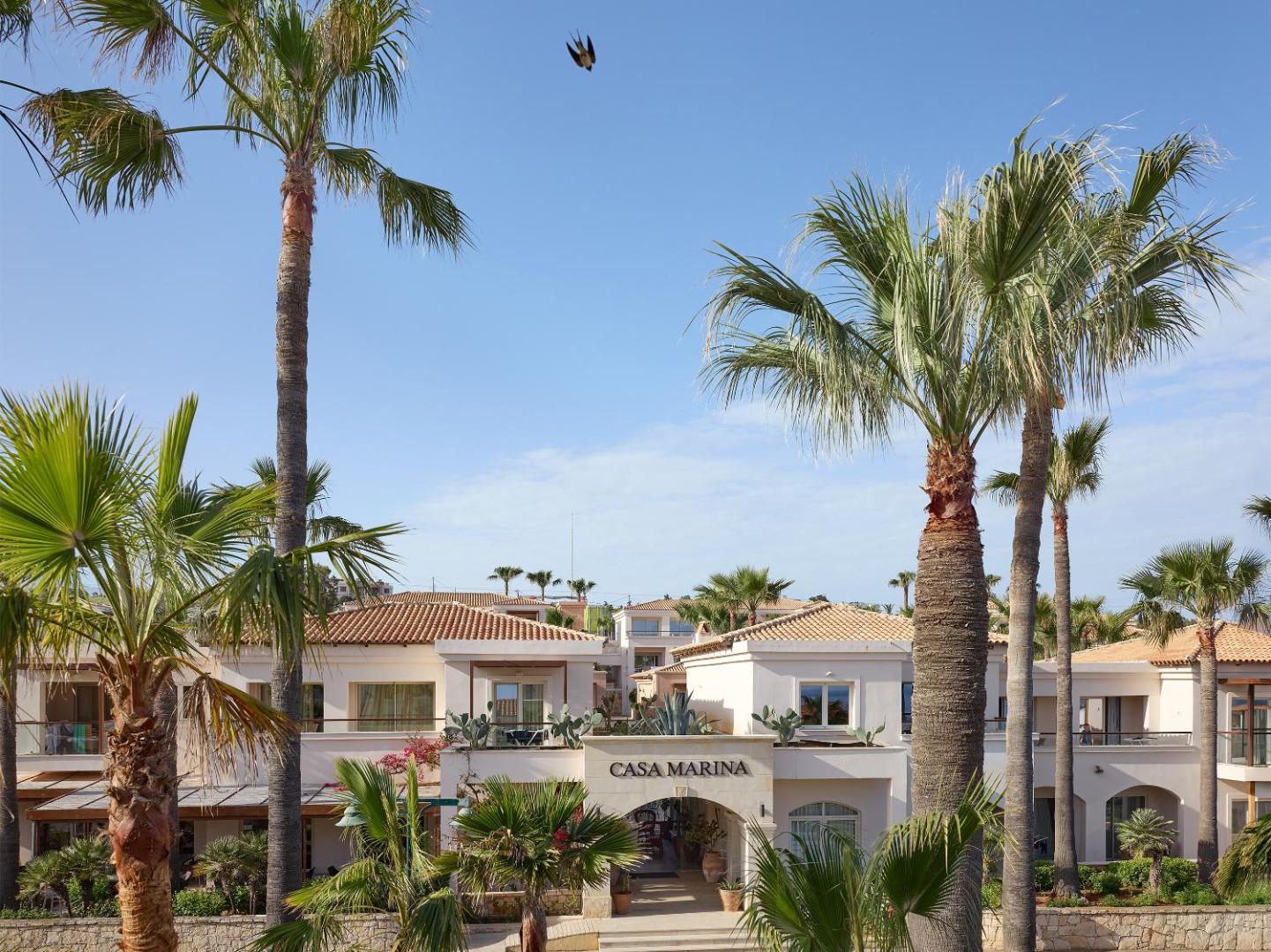 Grecotel Marine Palace & Aqua Park viesnīcas ieeja Casa Marina zonā ar palmām un tradicionālo grieķu arhitektūru