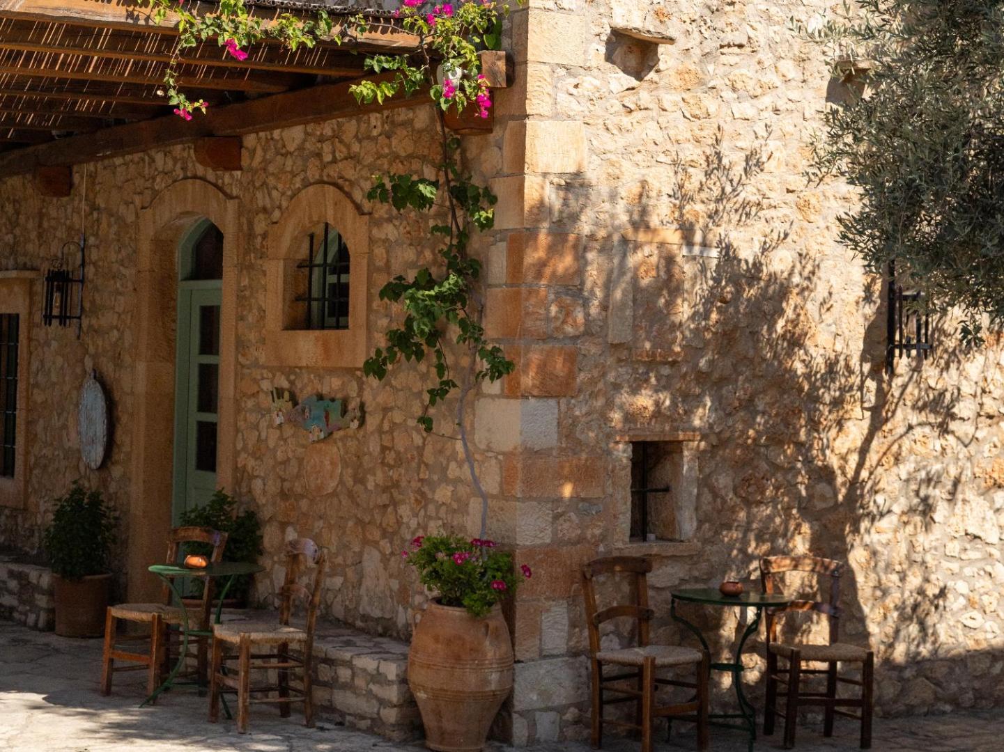 Grecotel Marine Palace & Aqua Park tradicionāla akmens mūra ēka ar ziedošām bugenvillijām un mājīgu āra terasi