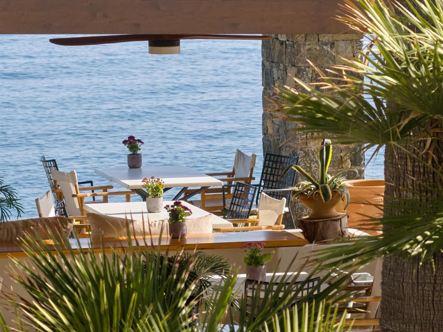 Grecotel Marine Palace & Aqua Park ēdienkartes restorāns pie pašas jūras ar baltiem galdiem un ziedu dekorācijām