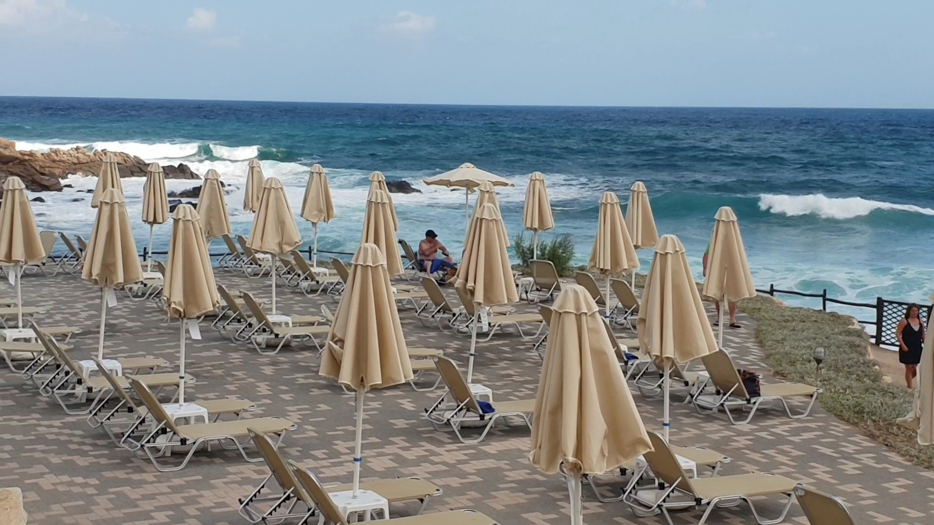 Grecotel Marine Palace & Aqua Park sauļošanās terase ar zviļņiem un saulessargiem tieši pie jūras krasta Krētā.