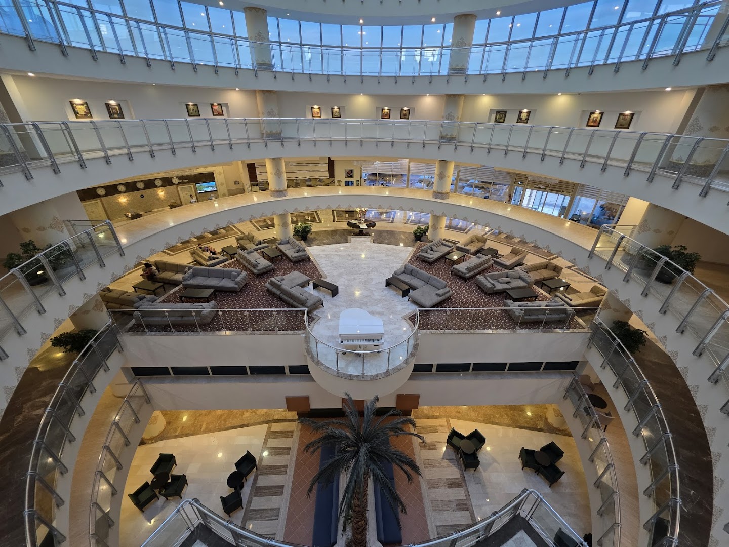 Skats no augšas uz Crystal Admiral Resort Suites & Spa daudzlīmeņu ātriju ar atpūtas dīvāniem un balto flīģeli centrā