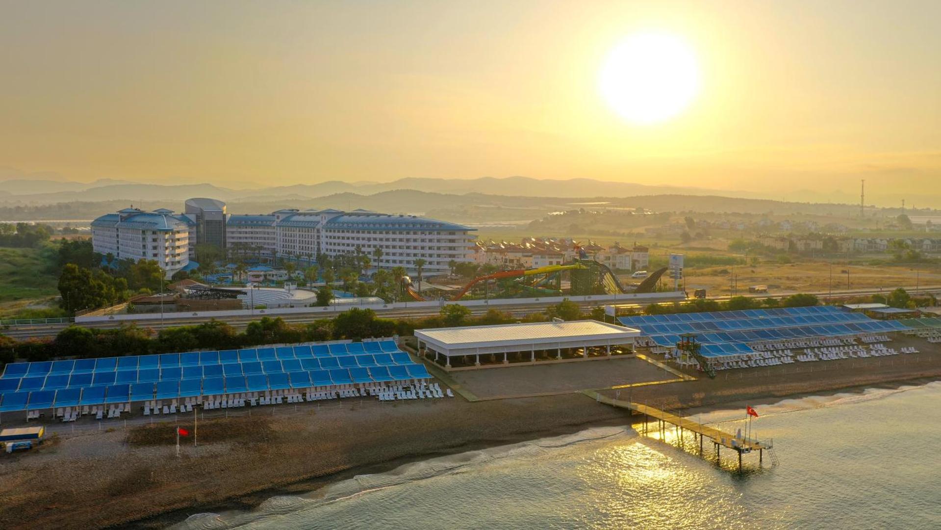 Saulriets virs Crystal Admiral Resort Suites & Spa — skats no putna lidojuma uz viesnīcas ēkām, pludmali un piestātni