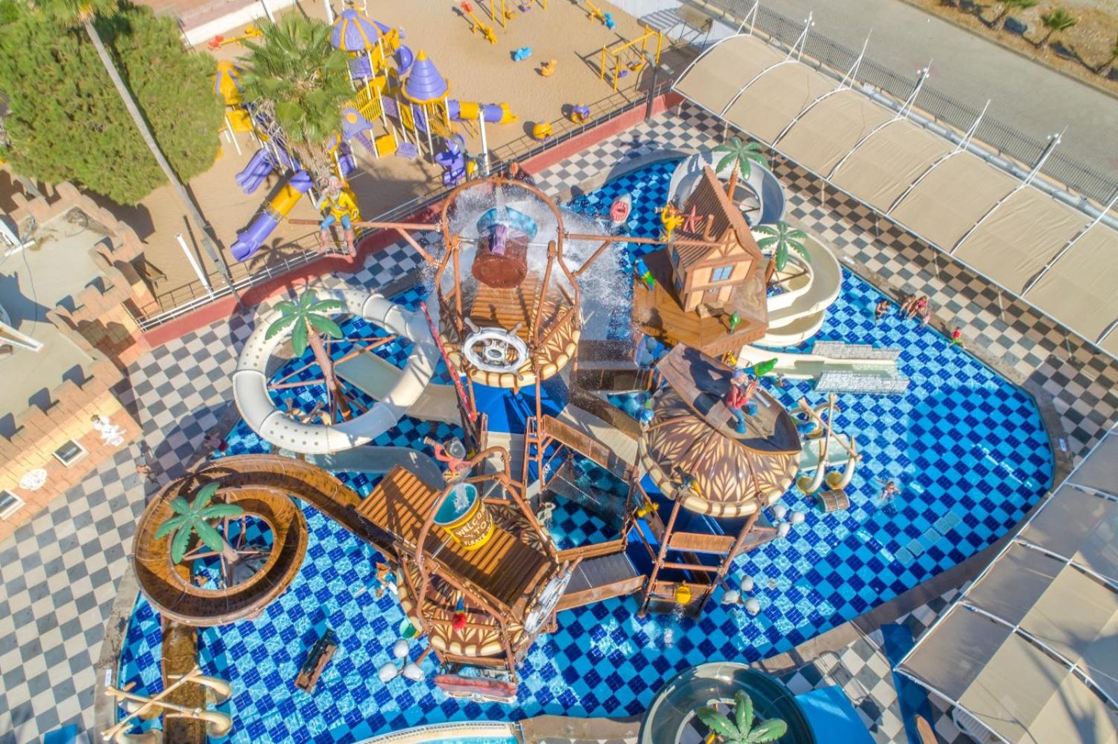 Skats no augšas uz Crystal Admiral Resort bērnu ūdens atrakciju parku ar pirātu tematikas dekorācijām un zili baltu flīžu baseinu
