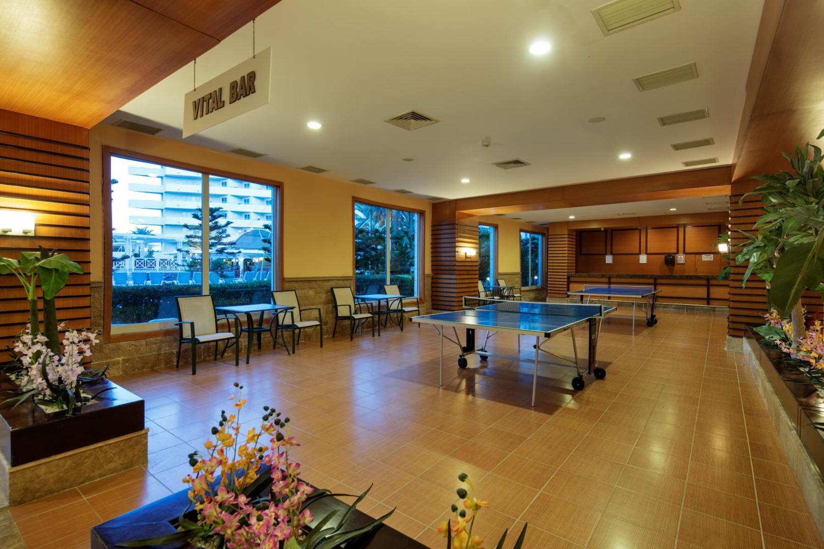 Crystal Admiral Resort Suites & Spa atpūtas telpa Vital Bar ar galda tenisa galdiem un skatu uz dārzu caur lieliem logiem