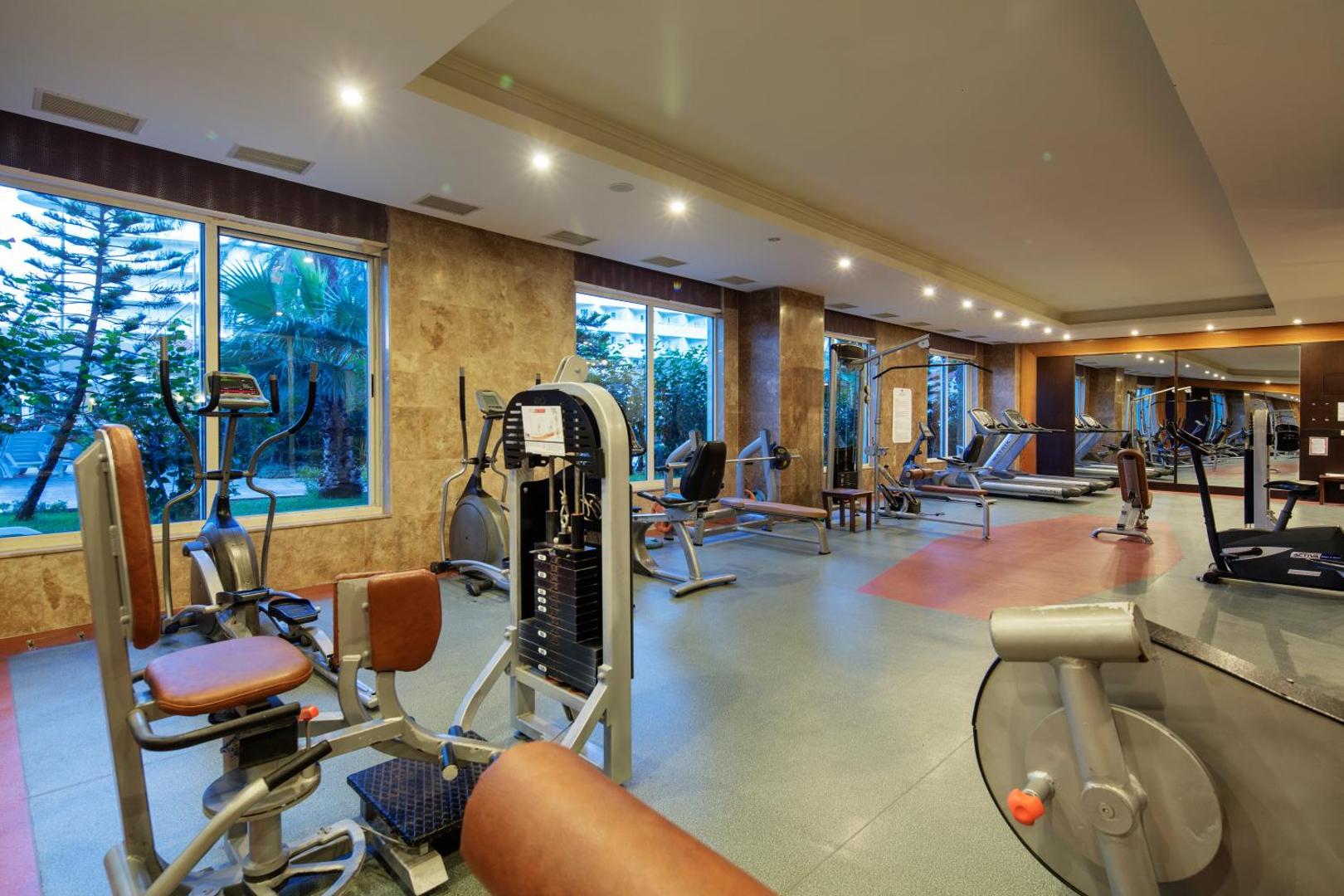 Crystal Admiral Resort Suites & Spa trenažieru zāle ar modernu fitnesa aprīkojumu, skrejceļiem un skatu uz palmu dārzu