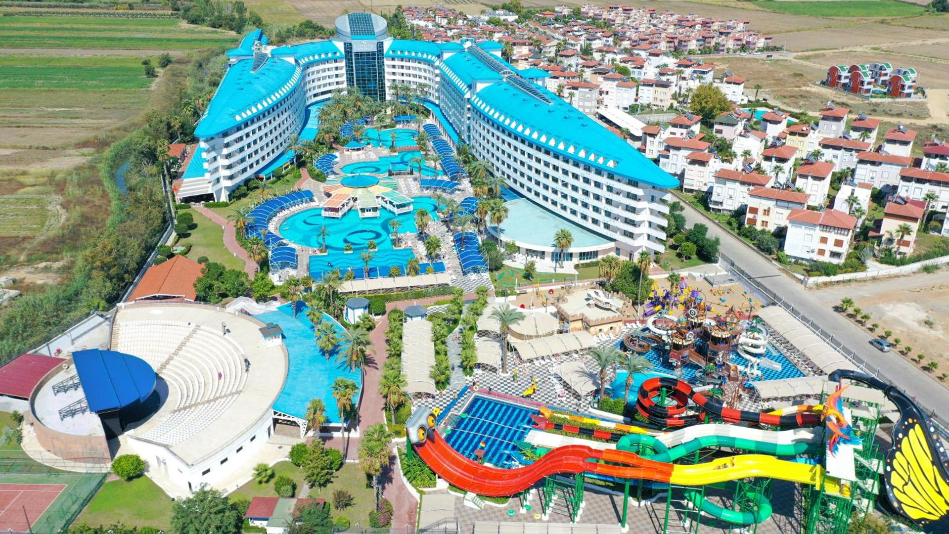 Crystal Admiral Resort Suites & Spa aerofoto — liels akvaparks ar krāsainiem slidkalniņiem, vairāki baseini un amfiteātris Turcijas piekrastē