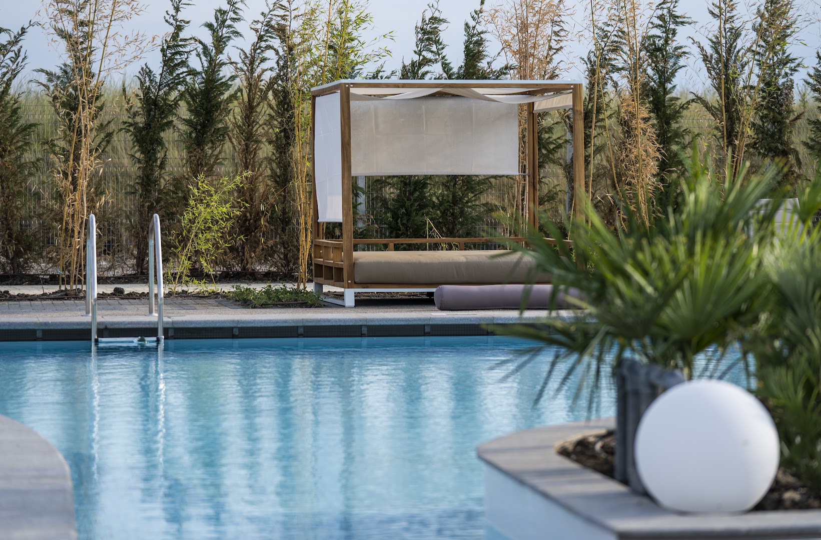 The Wave Resort āra atpūtas zona ar greznu sauļošanās gultu pie baseina un dekoratīviem apstādījumiem