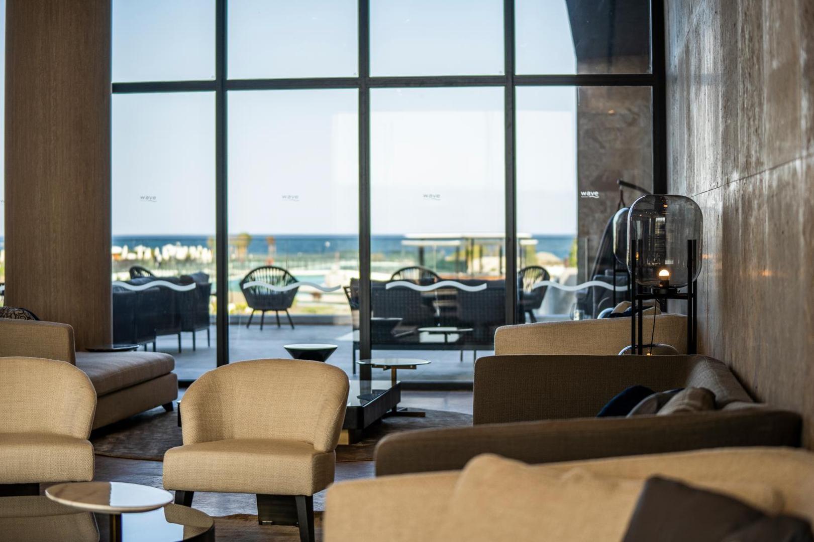 The Wave Resort lobby atpūtas zona ar ērtiem krēsliem un skatu caur lielajiem logiem uz Melno jūru un kūrorta teritoriju