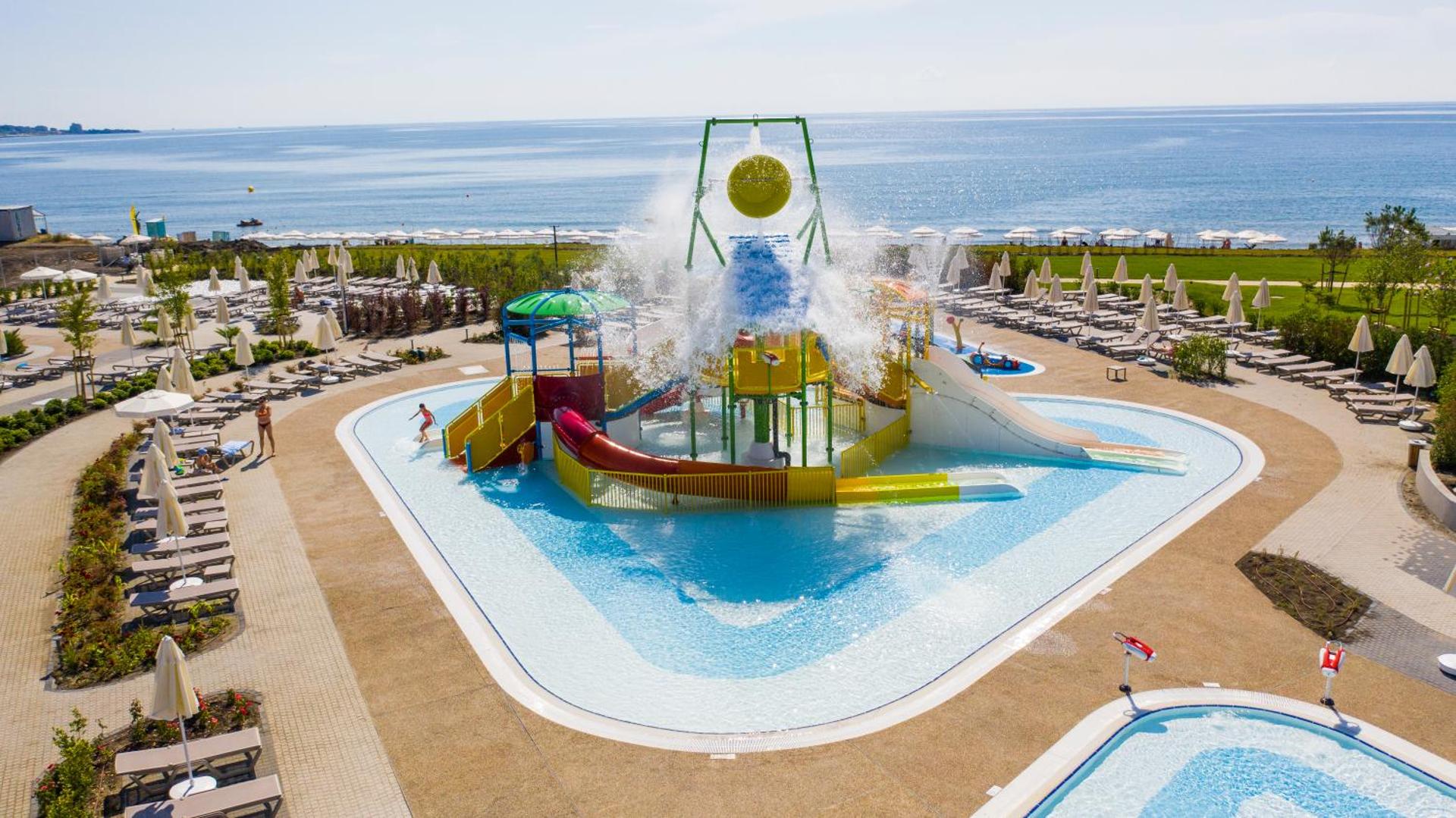 The Wave Resort akvaparks ar krāsainiem slidkalniņiem un ūdens spaiņiem pie jūras — plaša atpūtas zona ar sauļošanās krēsliem