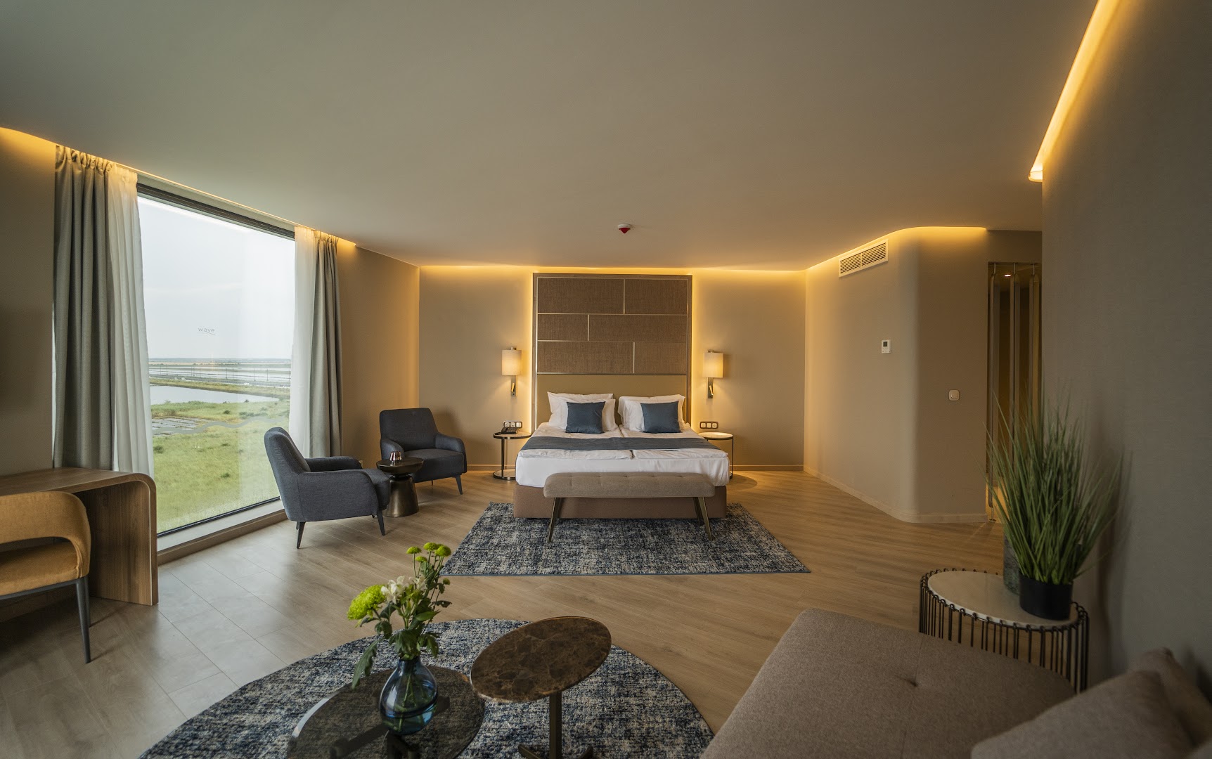 The Wave Resort moderns viesnīcas numurs ar panorāmas logu, divguļamo gultu un atpūtas zonu Bulgārijas piekrastē