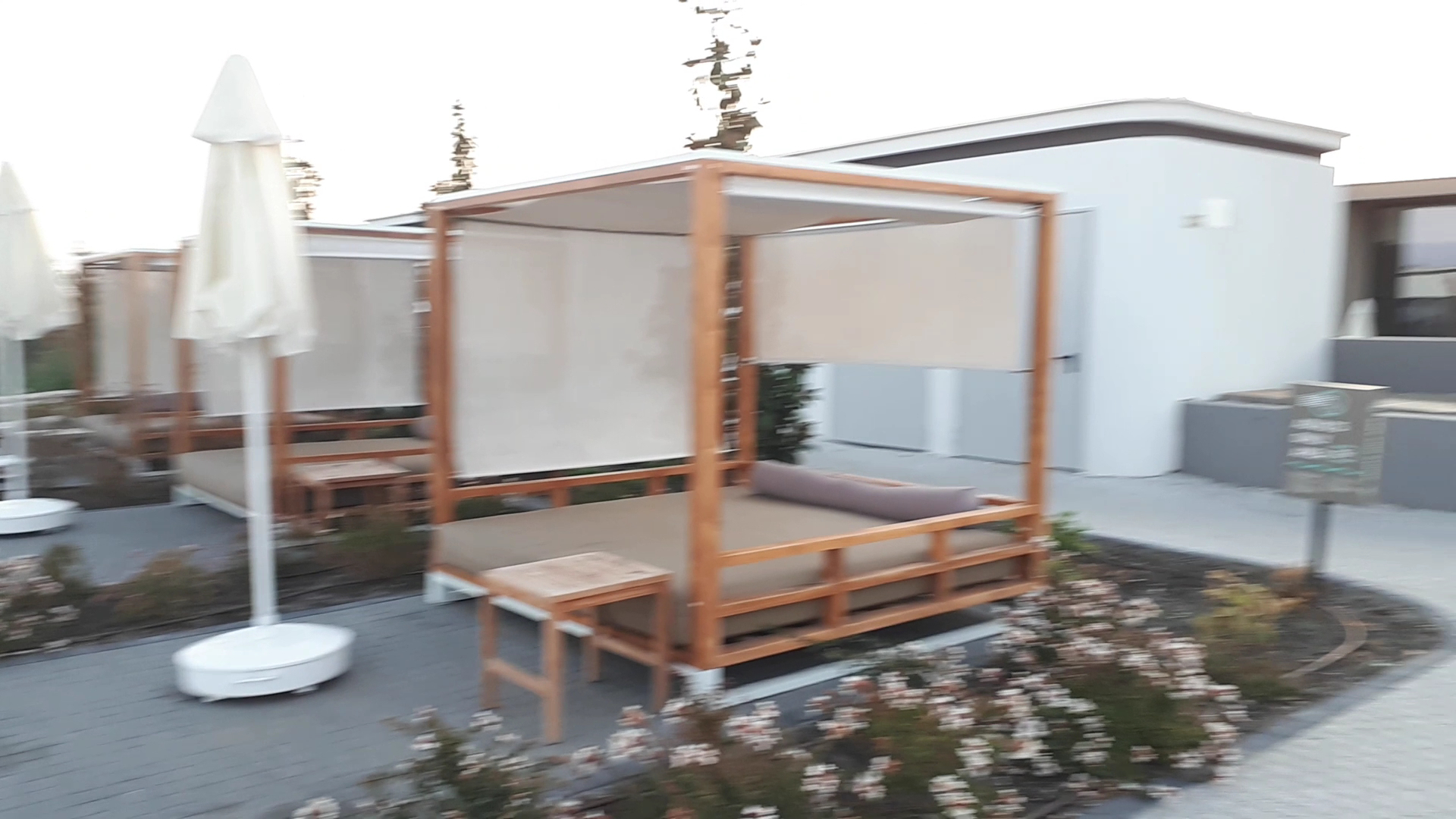 The Wave Resort āra atpūtas zona ar koka sauļošanās gultām un saulessargiem pie kūrorta ēkas.