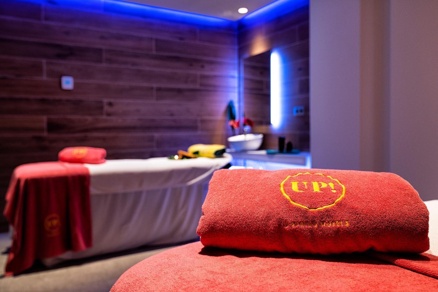 Hotel Bitacora masāžas kabinets ar sarkanu dvieli un mājīgu koka apdari — relaksējoša gaisotne spa centrā Tenerifē