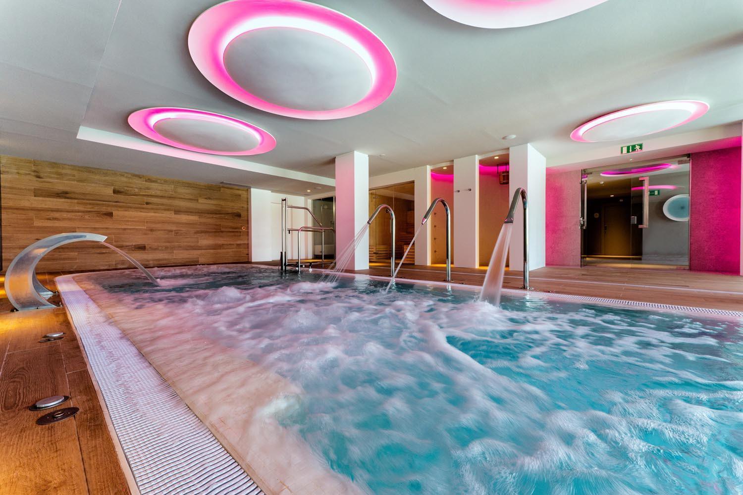 Hotel Bitacora iekštelpu spa baseins ar hidromasāžas strūklām un modernu rozā apgaismojumu Tenerifē — relaksācijas zona ar koka apdari