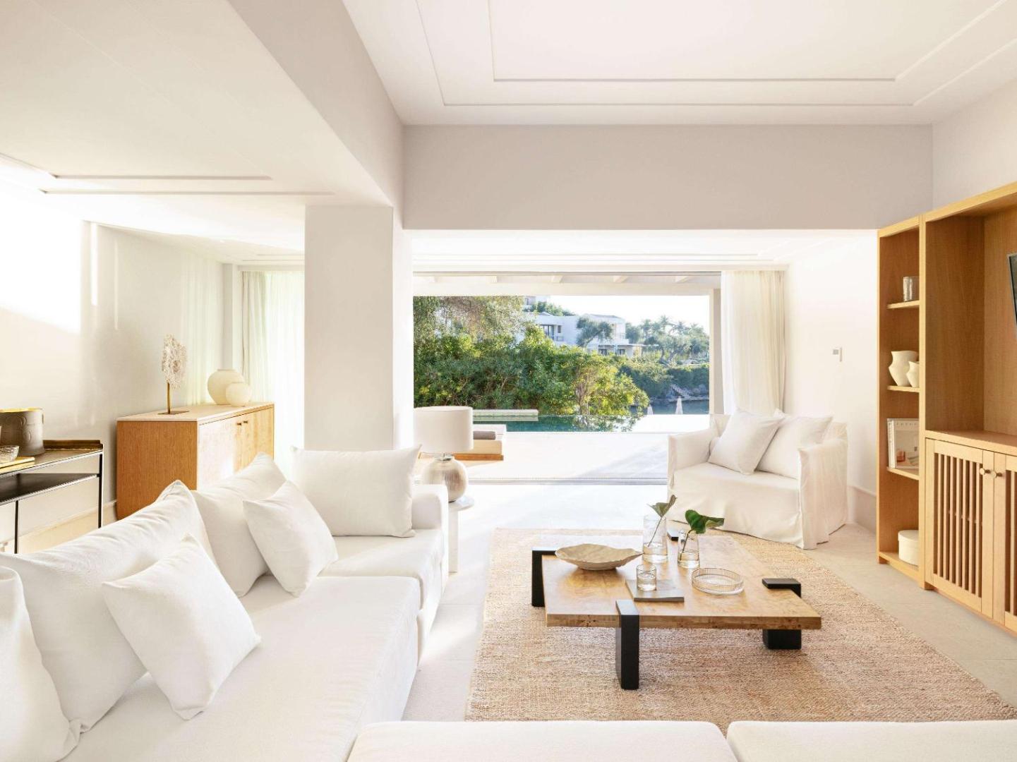 Corfu Imperial Grecotel Exclusive Resort moderna viesistaba ar minimālisma stila mēbelēm, koka akcentiem un izeju uz terasi