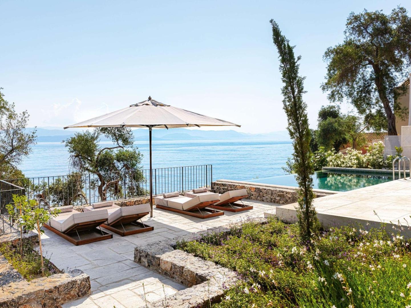 Atpūtas zona ar sauļošanās krēsliem un saulessargu pie Corfu Imperial Grecotel Exclusive Resort baseina Korfu salā