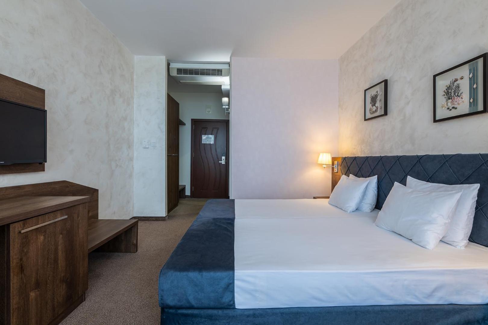 Flamingo Beach Hotel gaišs divvietīgs numurs ar tumši zilu gultas galvgali, koka mēbelēm un sienas dekorācijām Saulainajā krastā, Bulgārijā