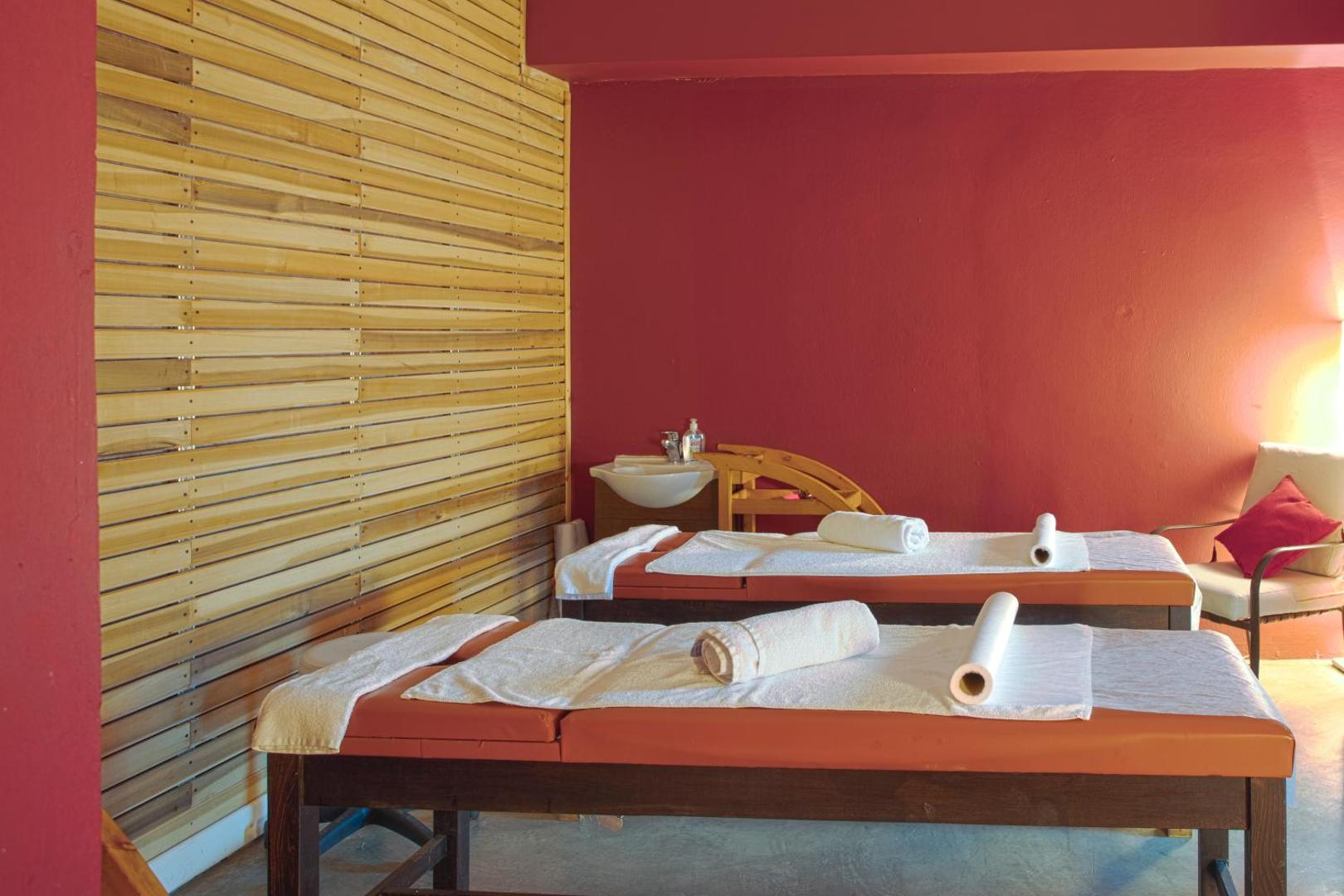 Spa procedūru telpa Corfu Holiday Palace viesnīcā ar diviem masāžas galdiem un siltu apgaismojumu mājīgā atmosfērā