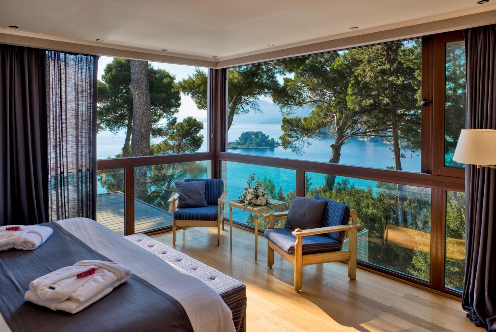 Corfu Holiday Palace viesnīcas numurs ar panorāmas logiem uz Jonijas jūru un Pontikonisi salu Korfu salā Grieķijā