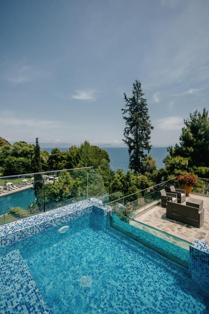 Corfu Holiday Palace numurs ar tiešu piekļuvi baseinam uz terases, stikla margām un skatu uz jūru un priežu mežu Korfu