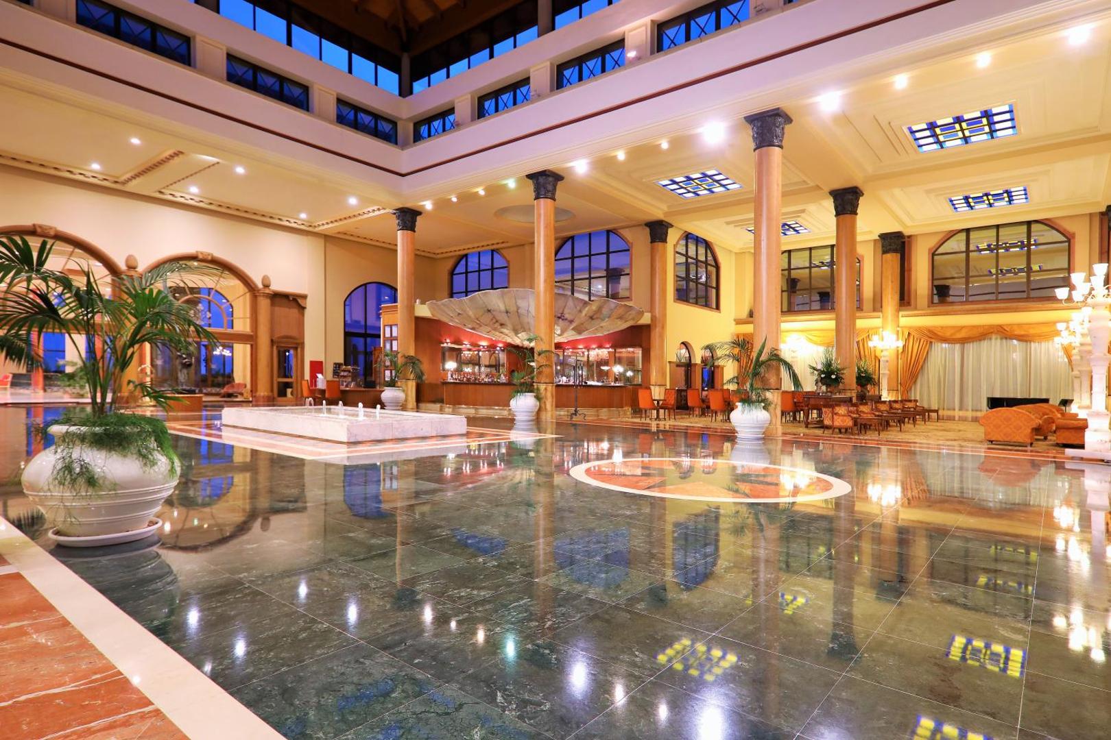 Iberostar Selection Anthelia viesnīcas plašais un greznais vestibils ar marmora grīdām, augstām kolonnām un lobby bāru vakara apgaismojumā
