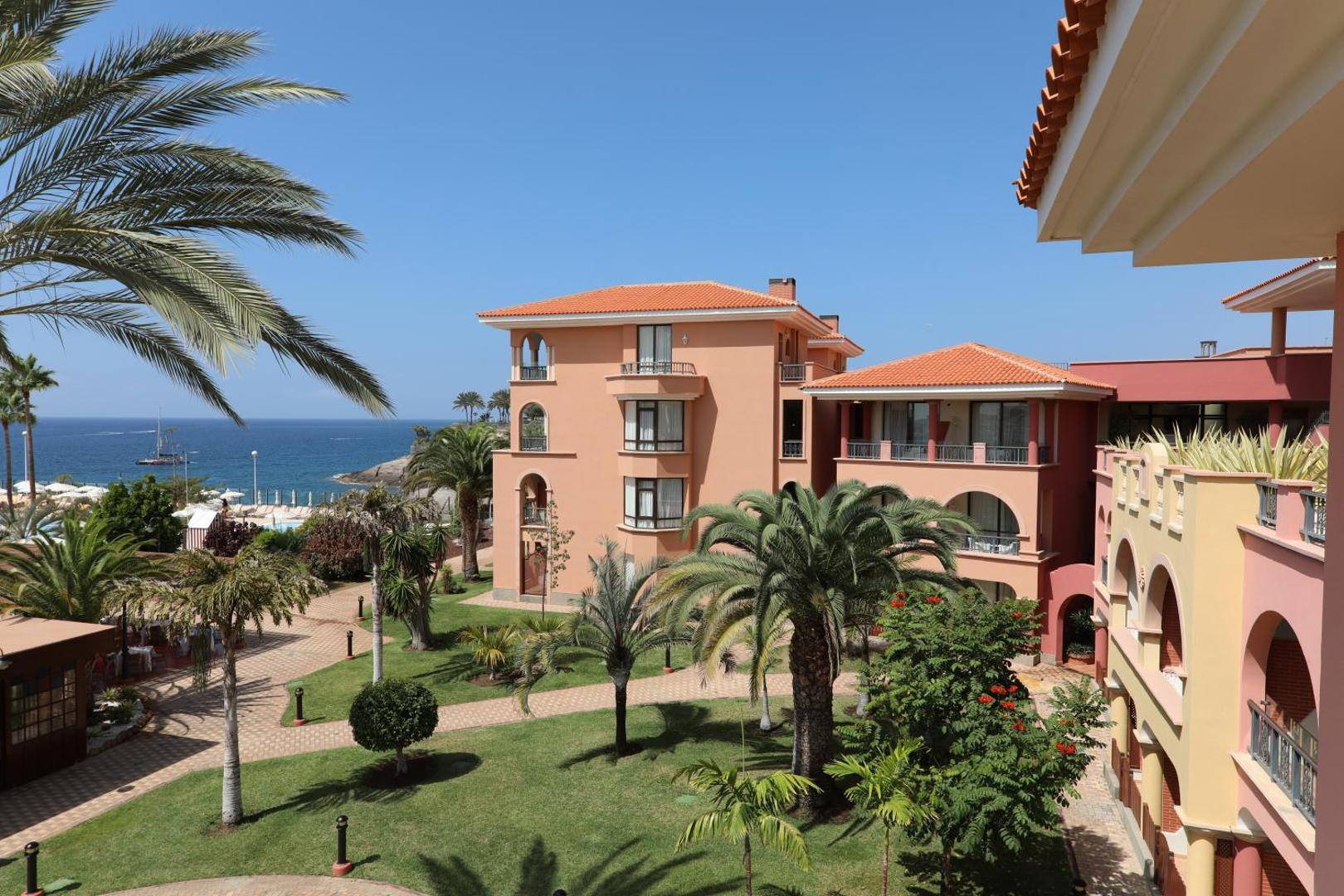 Iberostar Selection Anthelia viesnīcas korpusi ar terakotas krāsas fasādēm, dārzu un palmām piekrastē Kostadeje reģionā, Tenerifē