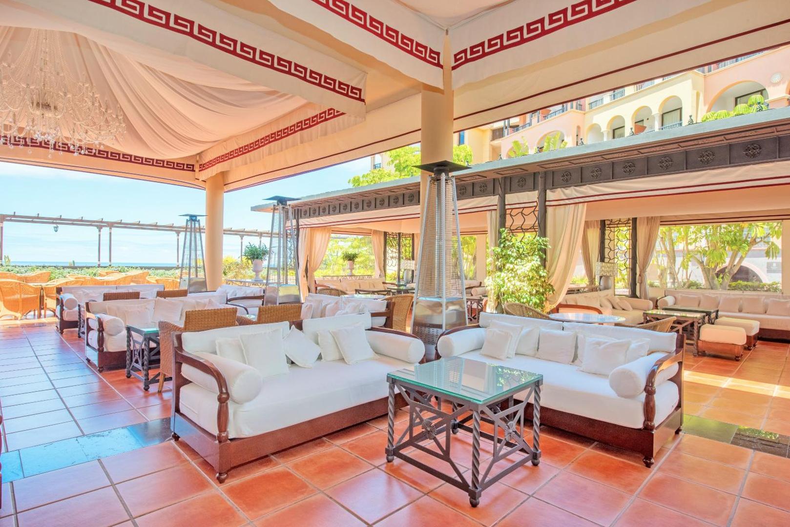 Iberostar Selection Anthelia āra terase ar baltiem dīvāniem, atpūtas zonu zem nojumes un skatu uz okeānu Tenerifes piekrastē