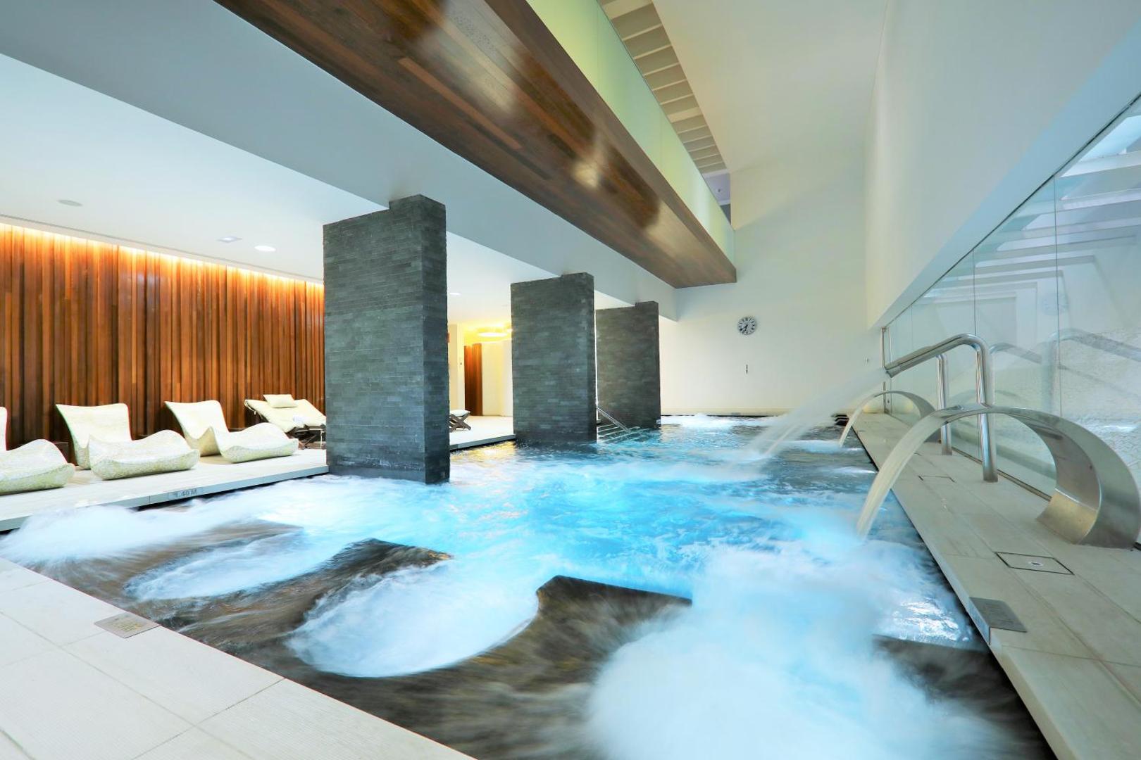 Iberostar Selection Anthelia spa centra iekštelpu baseins ar hidromasāžas strūklām, koka apdari un atpūtas krēsliem relaksācijai.