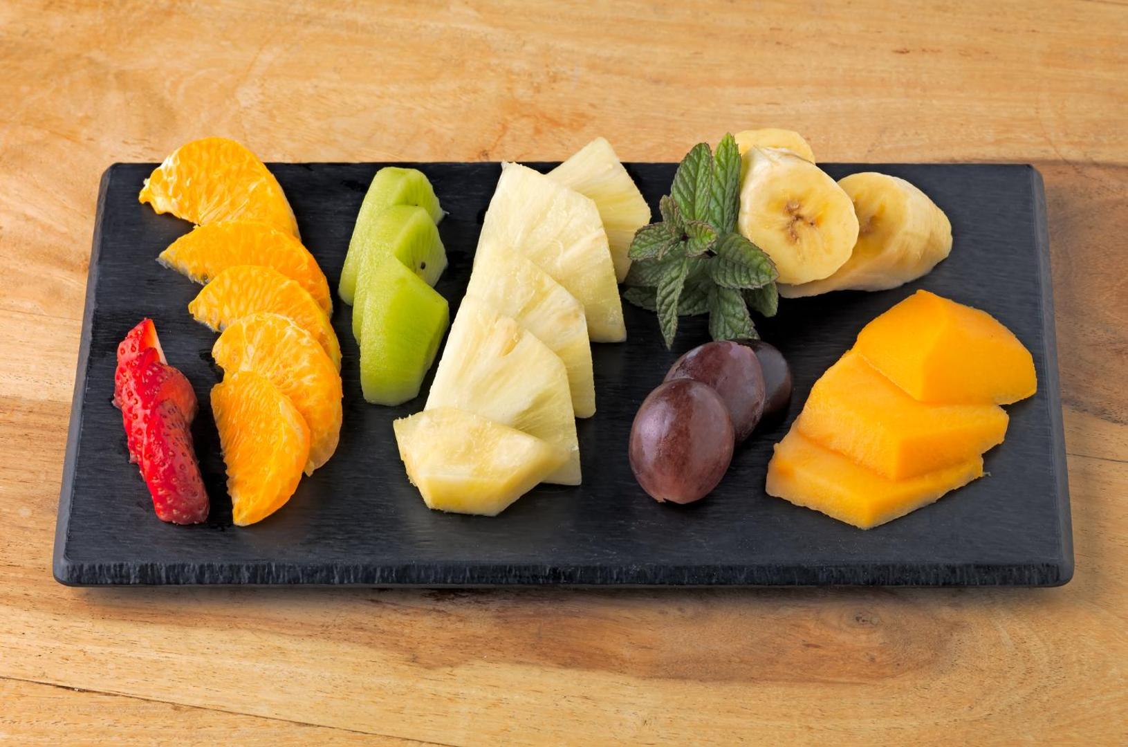 Svaigu augļu plate viesnīcā H10 Las Palmeras ar zemenēm, apelsīniem, kivi, ananasu, vīnogām un mango uz akmens dēlīša.