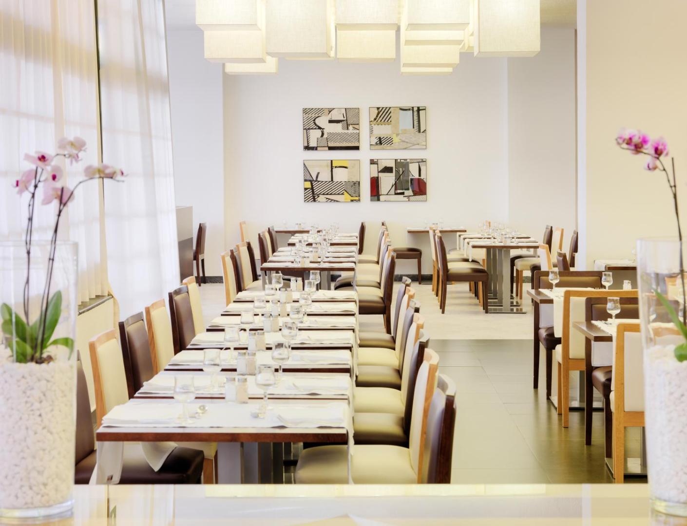 H10 Las Palmeras viesnīcas iekštelpu restorāns ar eleganti klātiem galdiem, modernu interjeru un gaišu apgaismojumu.
